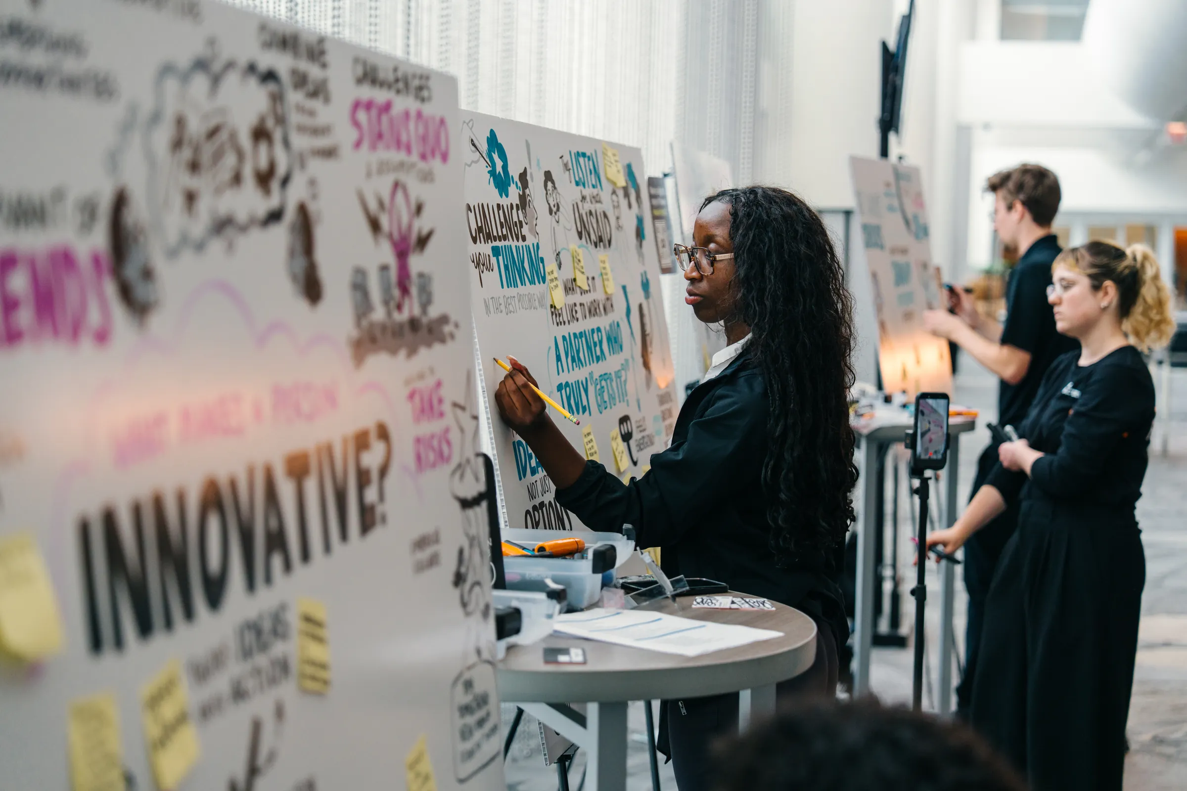 Graphic recorders illustrating session takeaways on large boards at the Key Partner Forum.