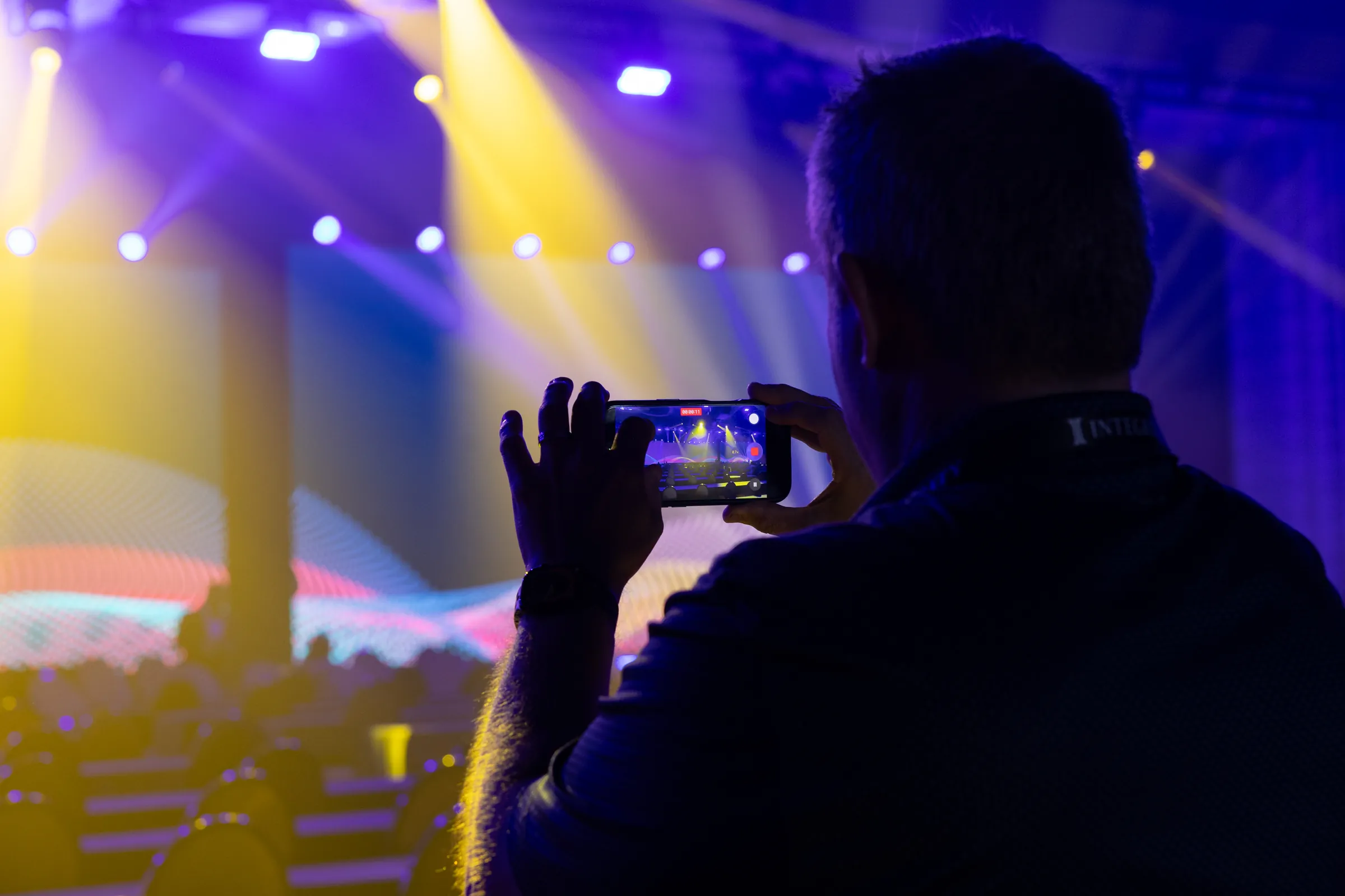 Attendee recording the stage show on his phone during the Integrity partner conference.
