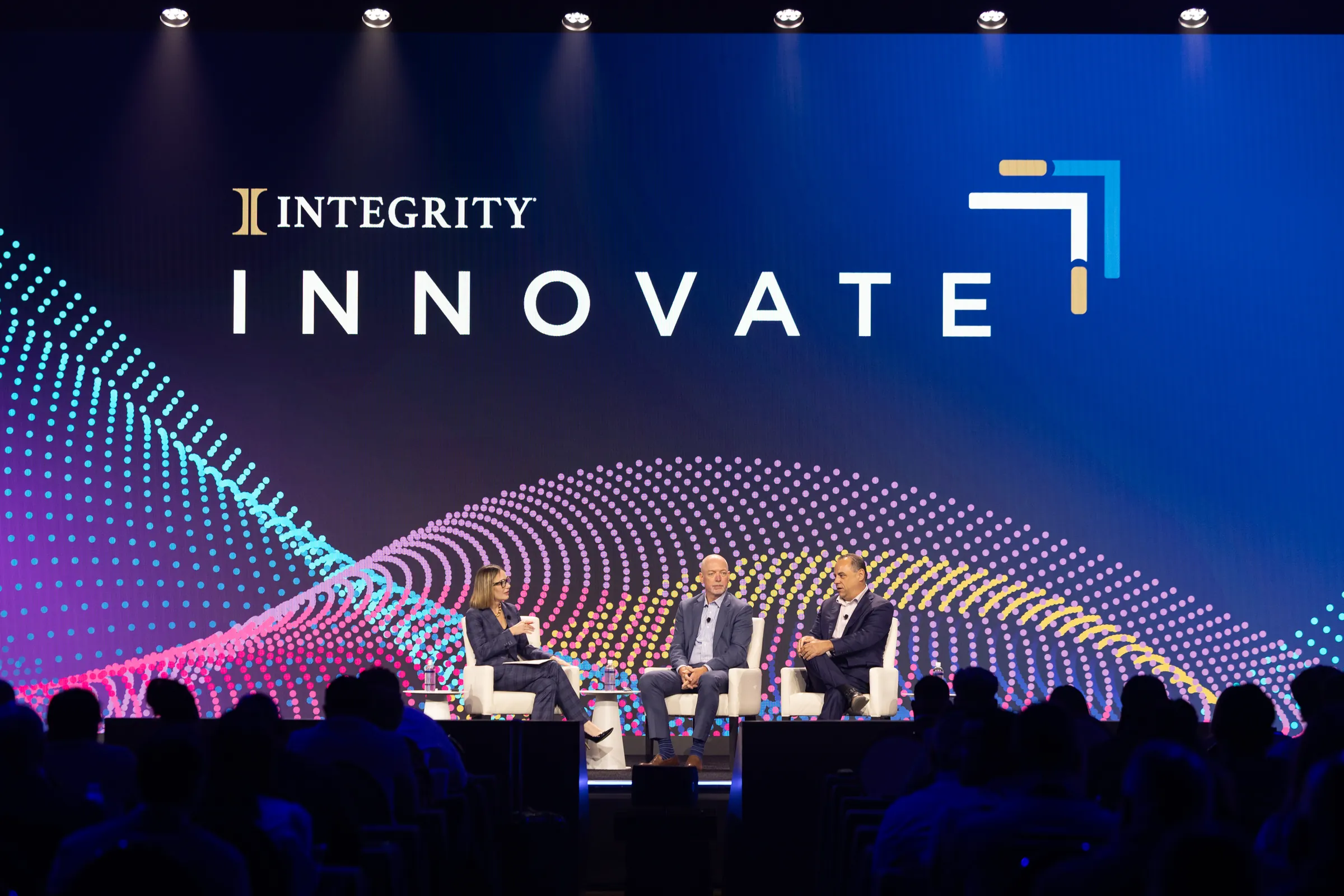 Three panelists seated on stage beneath the Integrity Innovate screen at the partner conference.