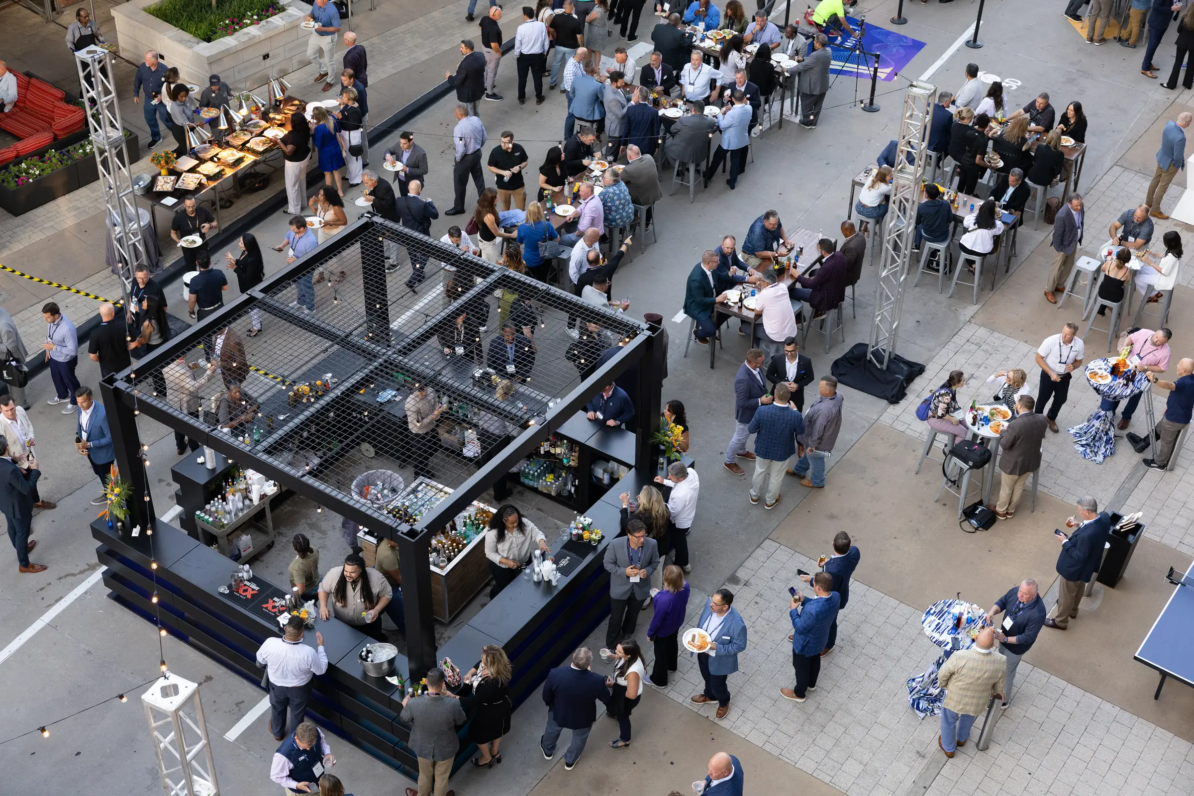 Aerial view of attendees at a custom outdoor bar and high-top tables during the Integrity reception.