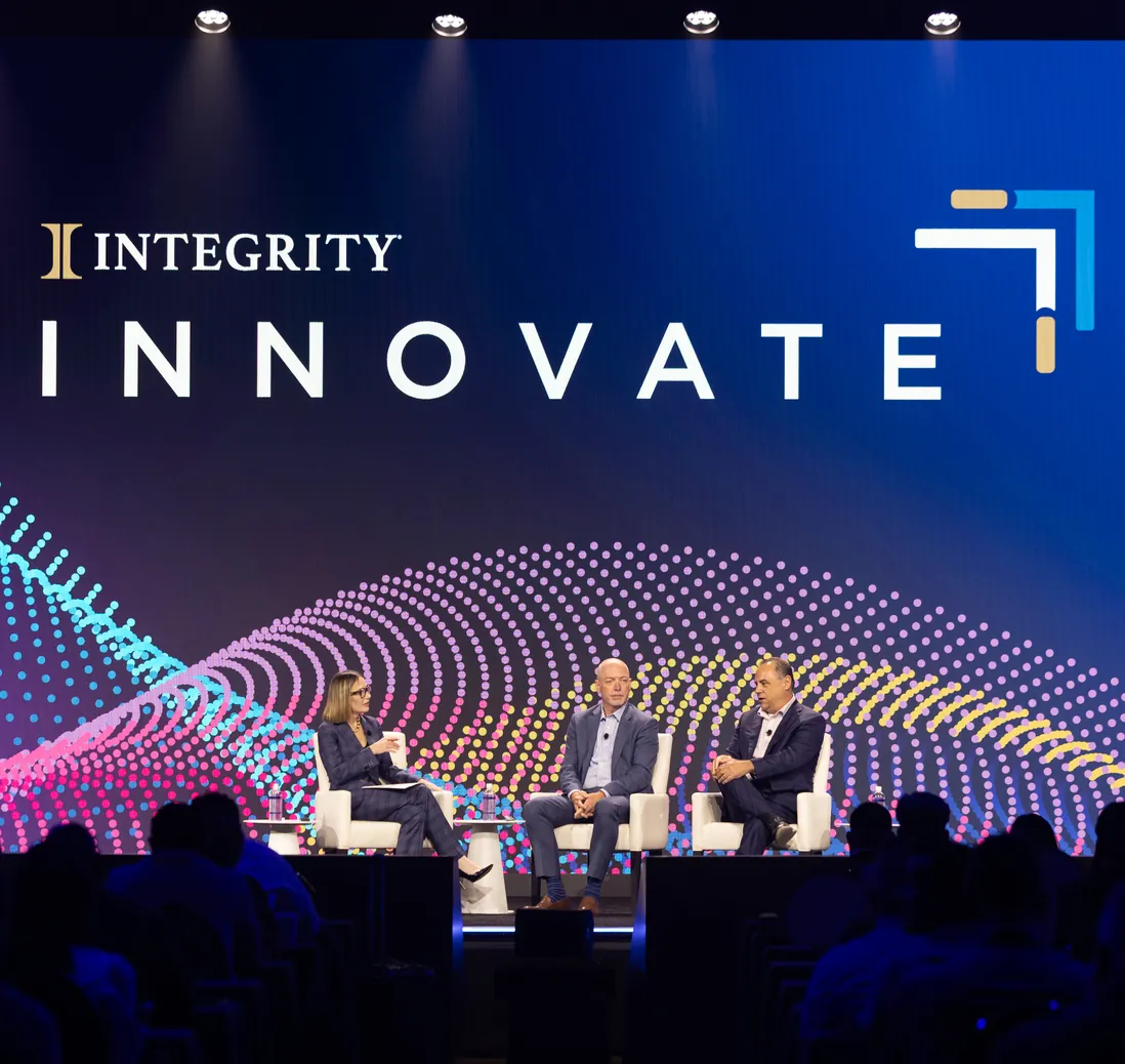 Three panelists seated on stage beneath the Integrity Innovate screen at the partner conference.